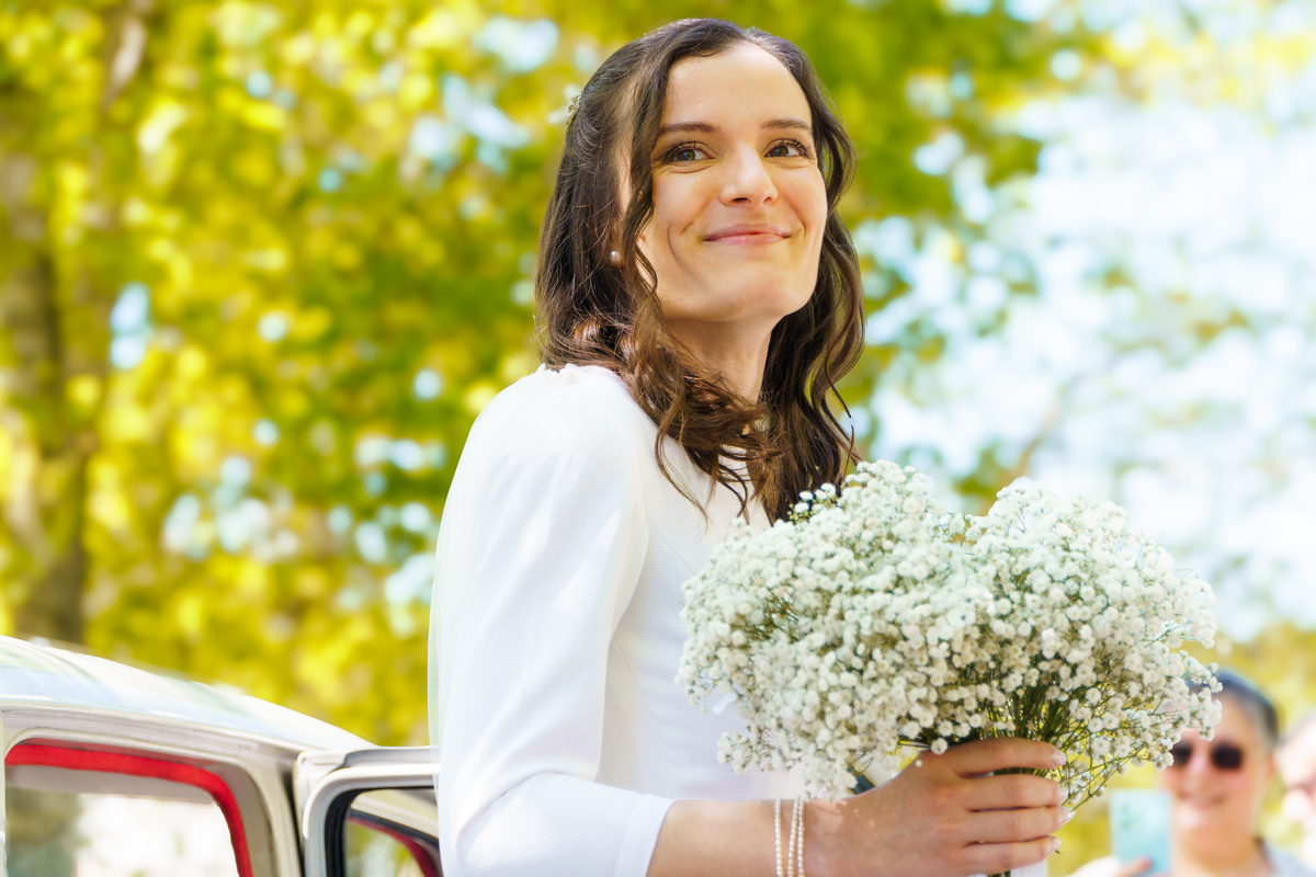 Mariée souriante tenant un bouquet de gypsophile, lumière dorée